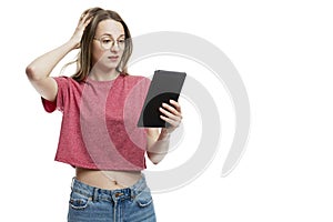 A young girl in glasses looks in surprise at the tablet. Online chat. Isolated on a white background. Space for text