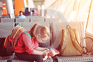 young girl with glasses playing with a doll at the airport, traveler