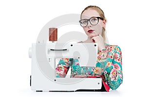 Young girl with glasses sews on a sewing machine, isolated on white background