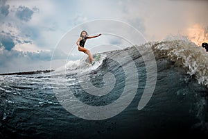 Young girl glides on a wakeboard in the river near forest