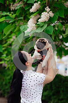 Young girl goes for walk with doggy pug in park. Selective focus