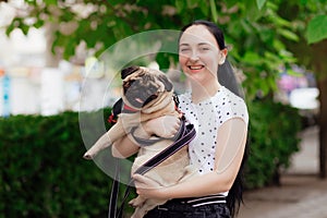 Young girl goes for walk with doggy pug in park. Selective focus