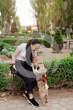 Young girl goes for walk with doggy pug in park. Selective focus