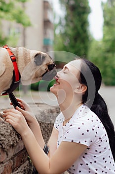 Young girl goes for walk with doggy pug in park. Selective focus