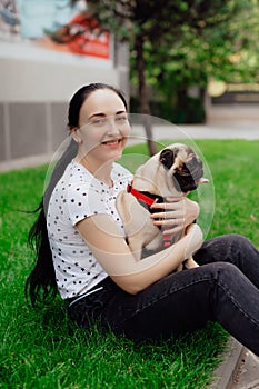 Young girl goes for walk with doggy pug in park. Selective focus