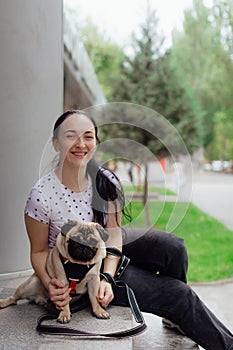 Young girl goes for walk with doggy pug in park. Selective focus