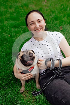 Young girl goes for walk with doggy pug in park. Selective focus