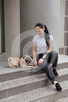 Young girl goes for walk with doggy pug in park. Selective focus