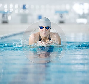 Young girl in goggles swimming breaststroke stroke style