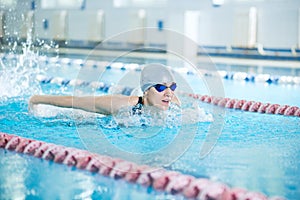 Young girl in goggles swimming butterfly stroke style