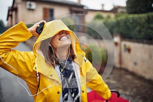 A young girl is in a good mood while walking and listening to the music on a rainy day. Walk, rain, city