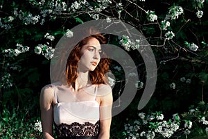 young girl with gorgeous dark red hair on a green background Flowers nature. Apple trees in bloom. Spring Garden. The concept of