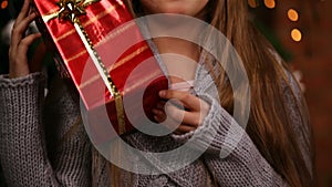 Young girl grabbing a christmas present lifting it to her face, laughing