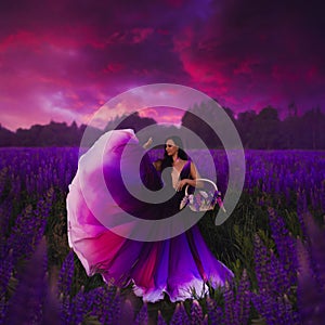 A young girl in a gradient haute couture dress standing in a blooming lupine field