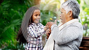 Young girl, grandmother and a surprise flower for senior woman or excited child or family bond with pensioner and giving