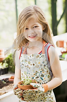 Young girl in greenhouse holding potted plant