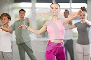 Young girl in group lesson with students rehearses, practices ballet dance, staging.