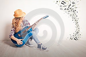 Young girl guitar play sitting on a floor