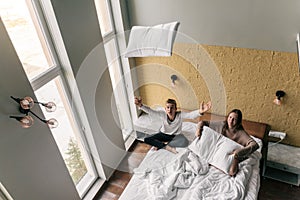 Young girl and guy relaxing on comfy bed in modern hotel room