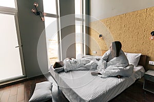 Young girl and guy relaxing on comfy bed in modern hotel room