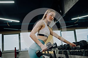 Young girl in the gym with dumbbells, Nice woman doing workout with dumbbells photo