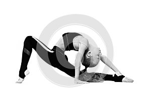 A young girl gymnast in a tracksuit does gymnastic stretching exercises. Black and white photo on a white background.