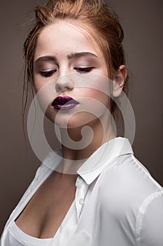 Young girl with a haircut in a white shirt. Beautiful model with nude make-up and bright lips. Office Style.