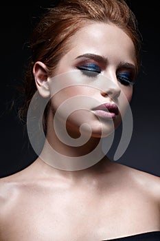 A young girl with a hairdo and a bright creative make-up. Beautiful model with red hair. Beauty of the face