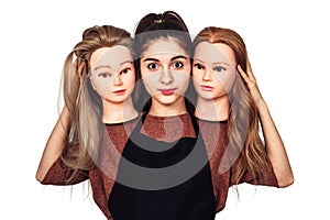 Young girl hairdresser holds in hands two mannequin heads. Woman with three heads.