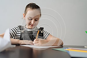 Young girl hand making craft using paper, scissors and pencils