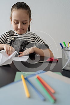 Young girl hand making craft using paper, scissors and pencils