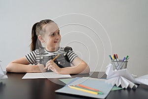 Young girl hand making craft using paper, scissors and pencils