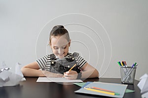 Young girl hand making craft using paper, scissors and pencils