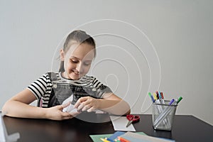 Young girl hand making craft using paper, scissors and pencils