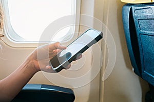 young girl hand using smartphone on airplane