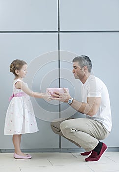 Young girl handing present to her father