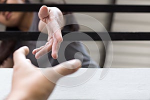 Young girl Hands reaching out from metal bars helping people