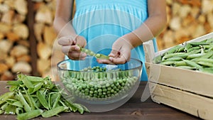 Young girl hands shelling peas into glass bow