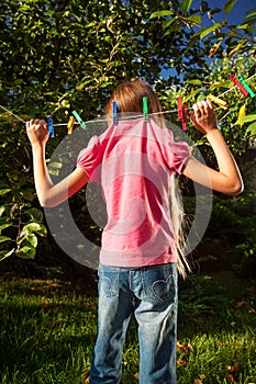 Young girl hanging on clothesline at garden