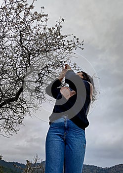 Young girl happy enjoying the blossoms of the almond tree in spring. Blooming flowers springtime