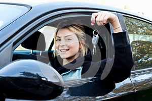 Young girl happy holding car key seated in her new car