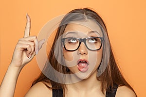 Young girl has an idea and pointing a finger upwards