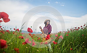 Young girl in hat walk in meadow. vacation. sense of freedom. beautiful woman gather red poppy flower bouquet in field