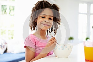 Young Girl Having Breakfast In Kitchen