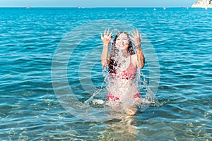 Young girl having fun while bathing in the sea and splashing water