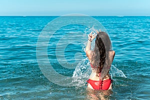 Young girl having fun while bathing in the sea and splashing water