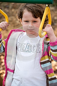 Young girl having fun outside at park on a playground swing set