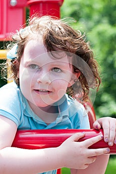 Young girl having fun outside at park on a playground swing set