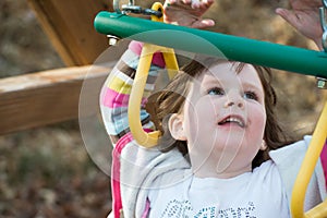 Young girl having fun outside at park on a playground swing set