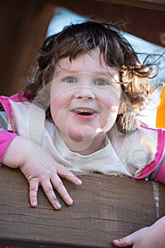 Young girl having fun outside at park on a playground swing set